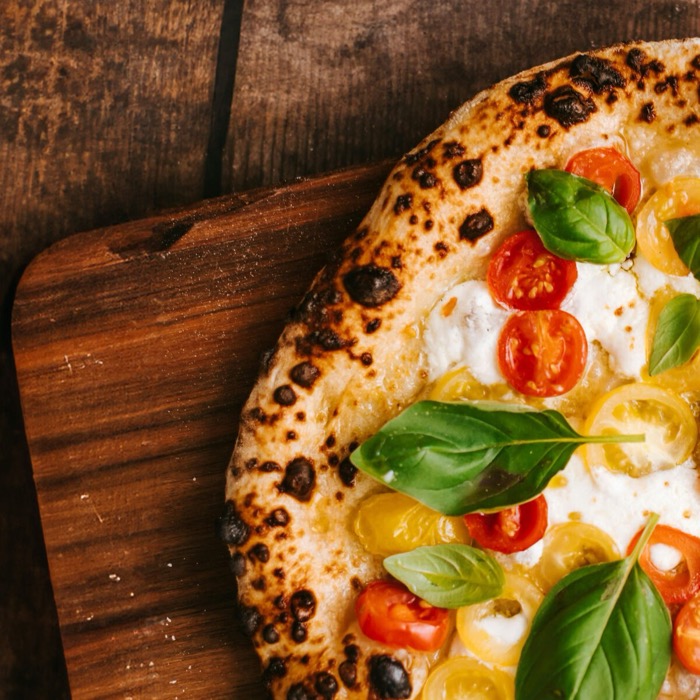 Detailaufnahme einer Pizza mit knusprigem Rand, geschmolzenem Mozzarella und frischem Basilikum